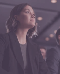 A woman sitting and listening attentively at an event or conference.