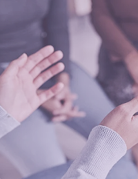 Children holding hands, focusing on their hands and arms, with blurred people in the background.