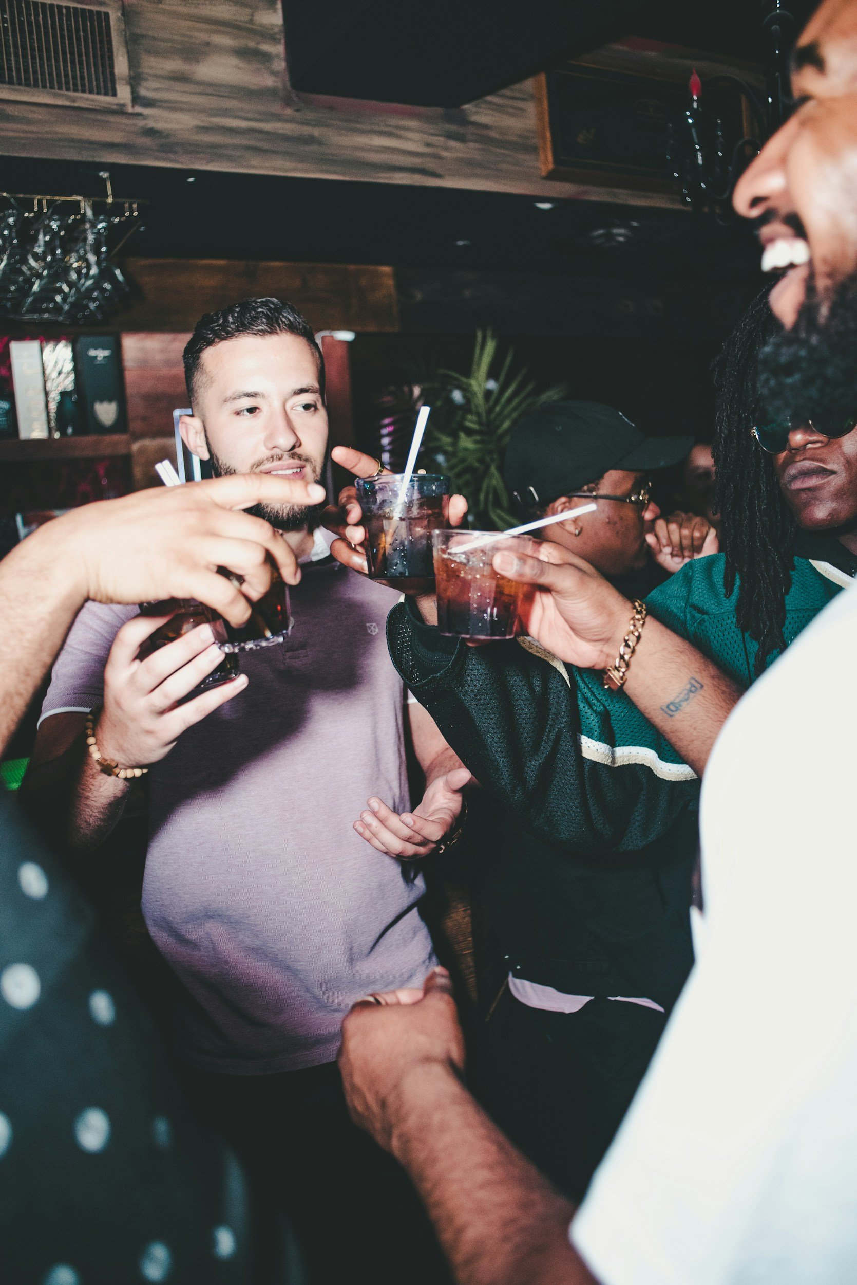 A group of friends with drinks in a social setting, smiling and enjoying each other's company.