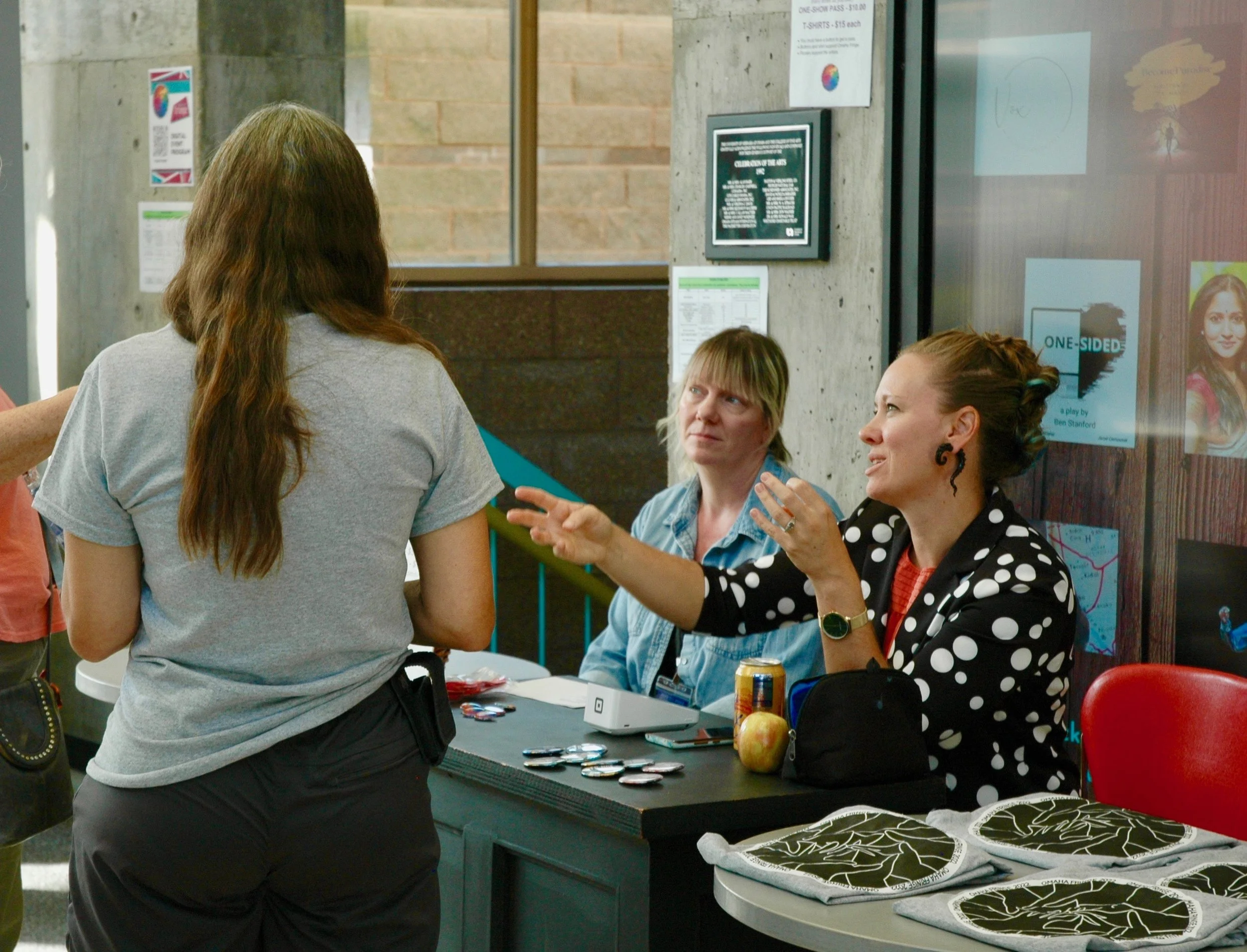 Woman at table talking to another person who is standing