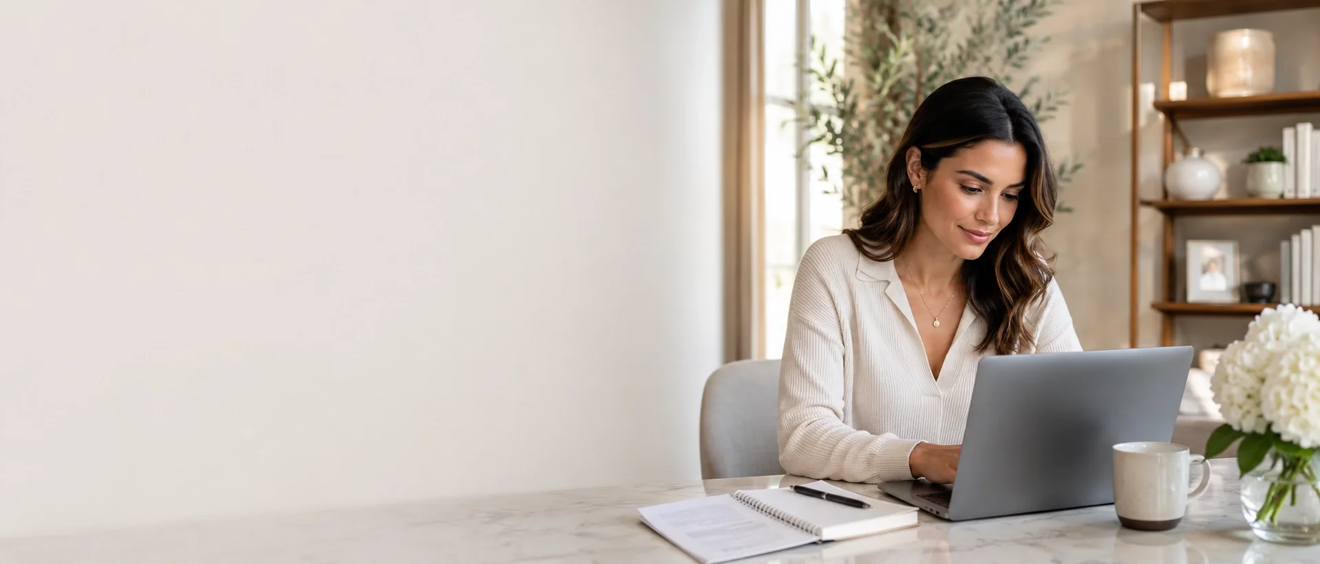 Female applicant applying for a job online from a laptop in a bright, modern home office setting.