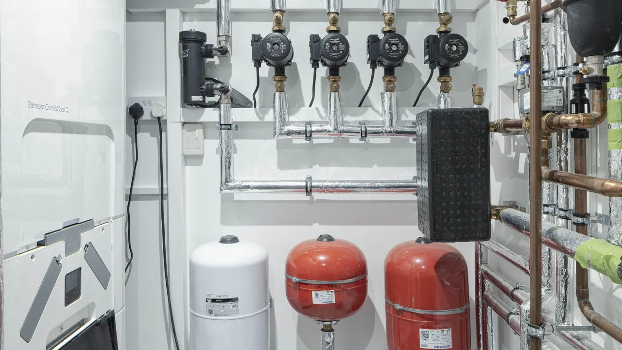Mechanical and plumbing control system with pumps, pipes, and pressure tanks in a utility room.