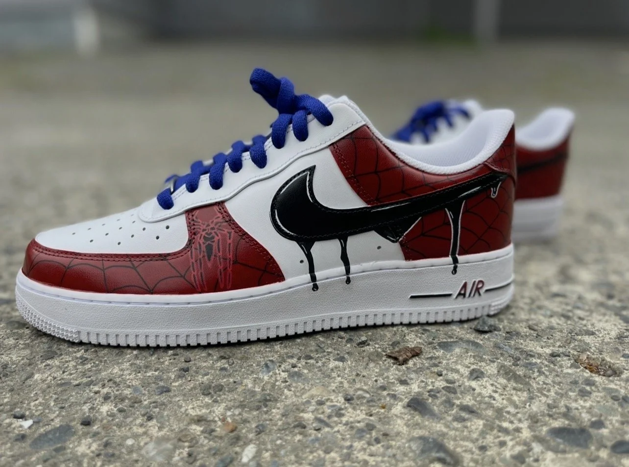 Custom Spider-Man Air Force 1 sneakers with hand-painted webbing artwork and blue laces.