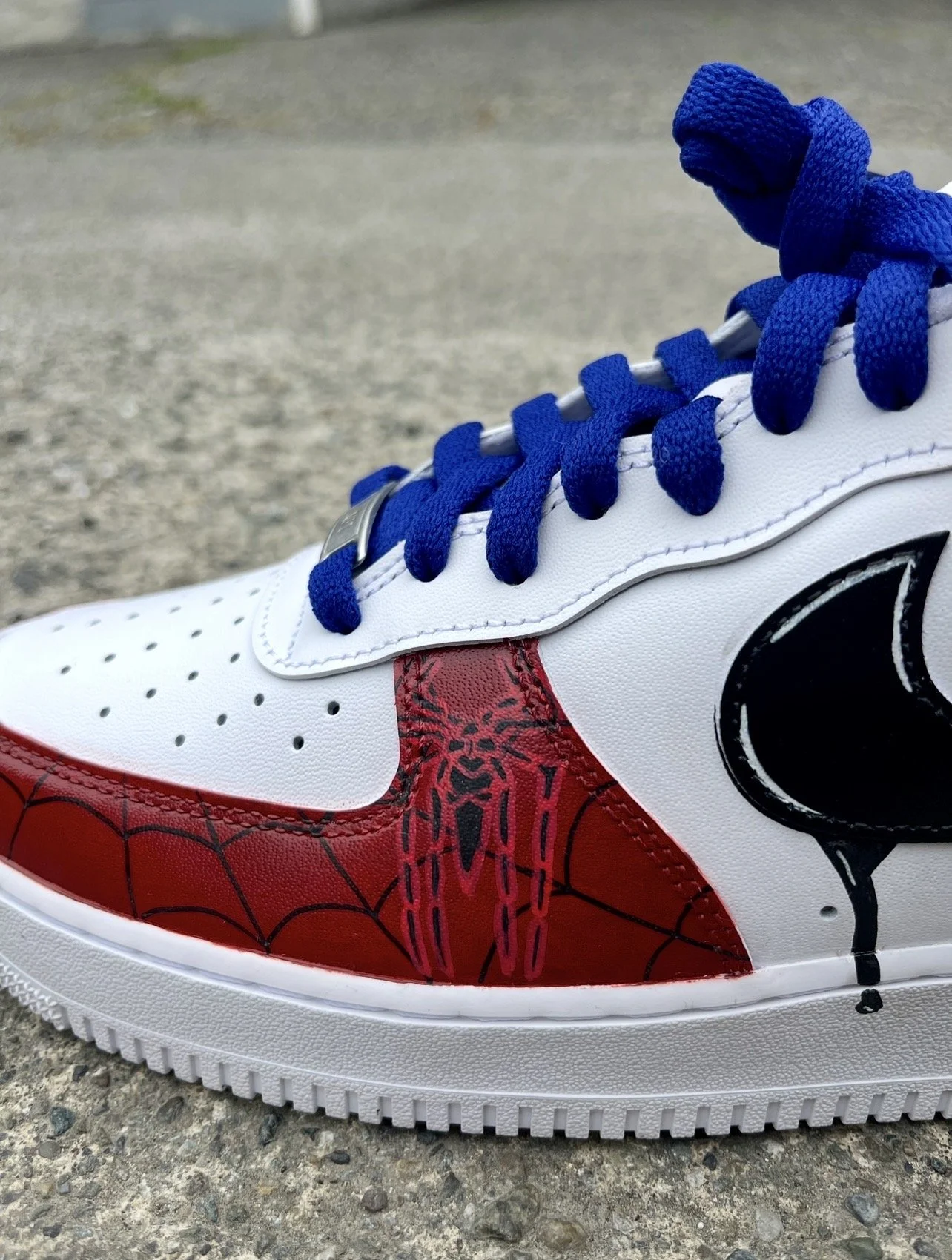 Close-up of hand-painted Spider-Man webbing and suit detail on custom Air Force 1 sneakers.