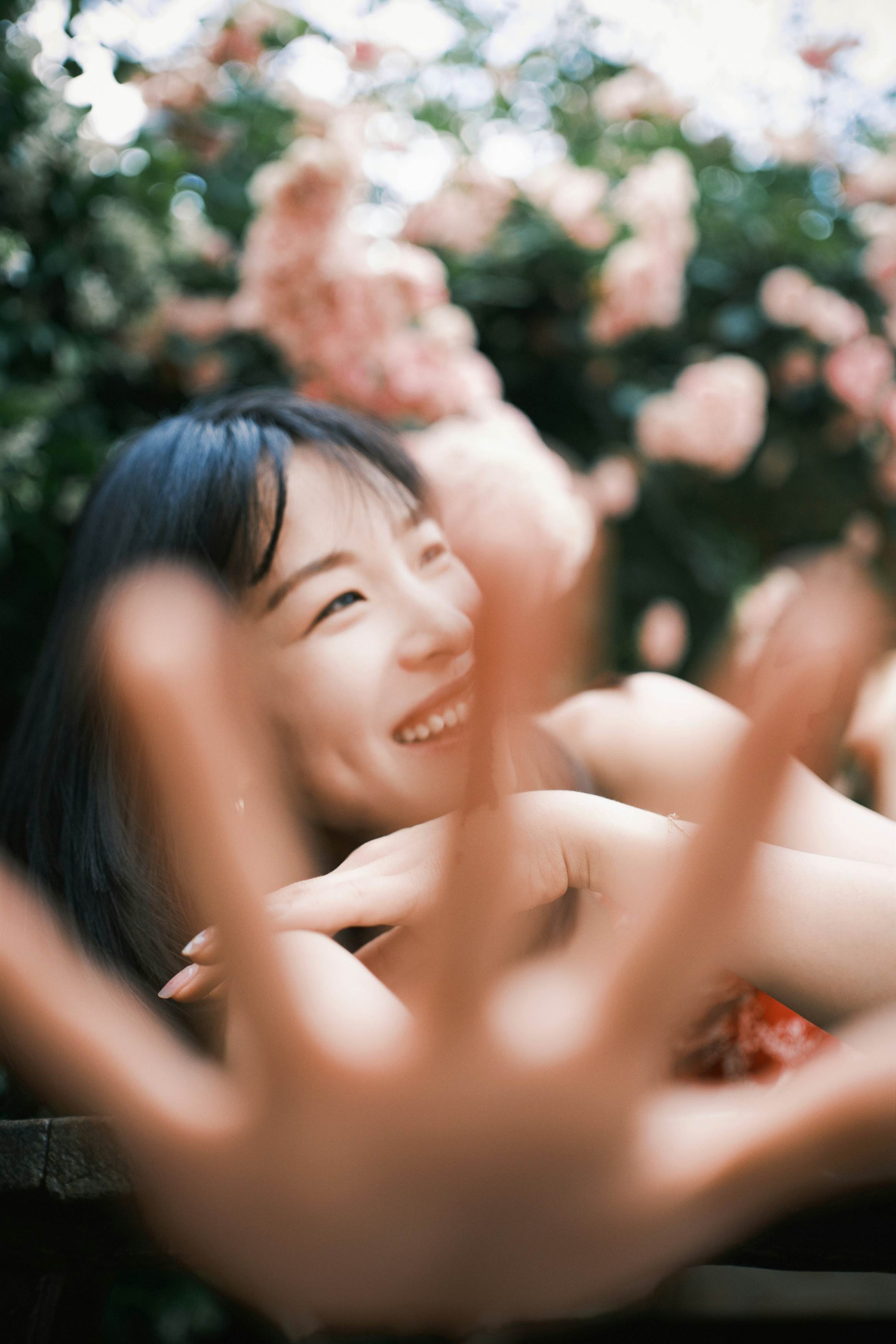 Woman smiling outdoors among flowers in soft natural light
