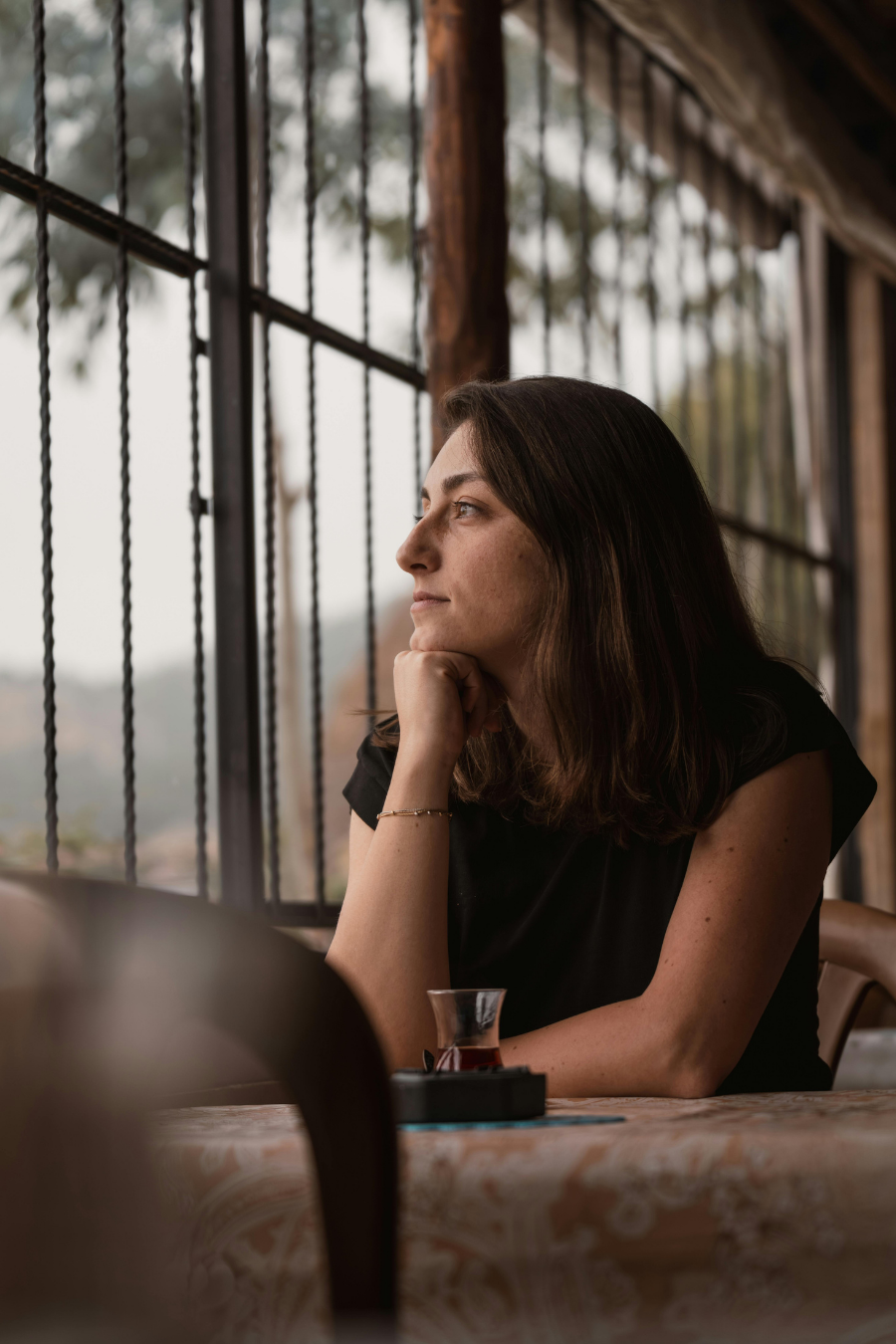 Woman resting her chin on her hand, gazing out a window