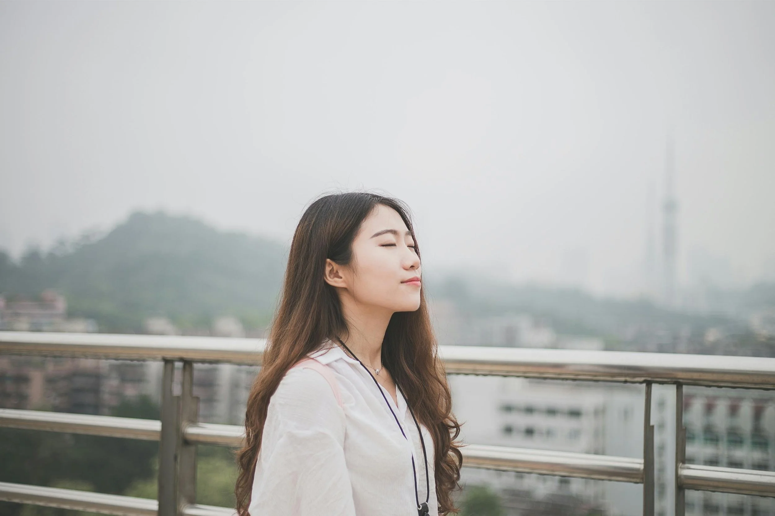 Woman standing outdoors with her eyes closed, looking calm and at peace