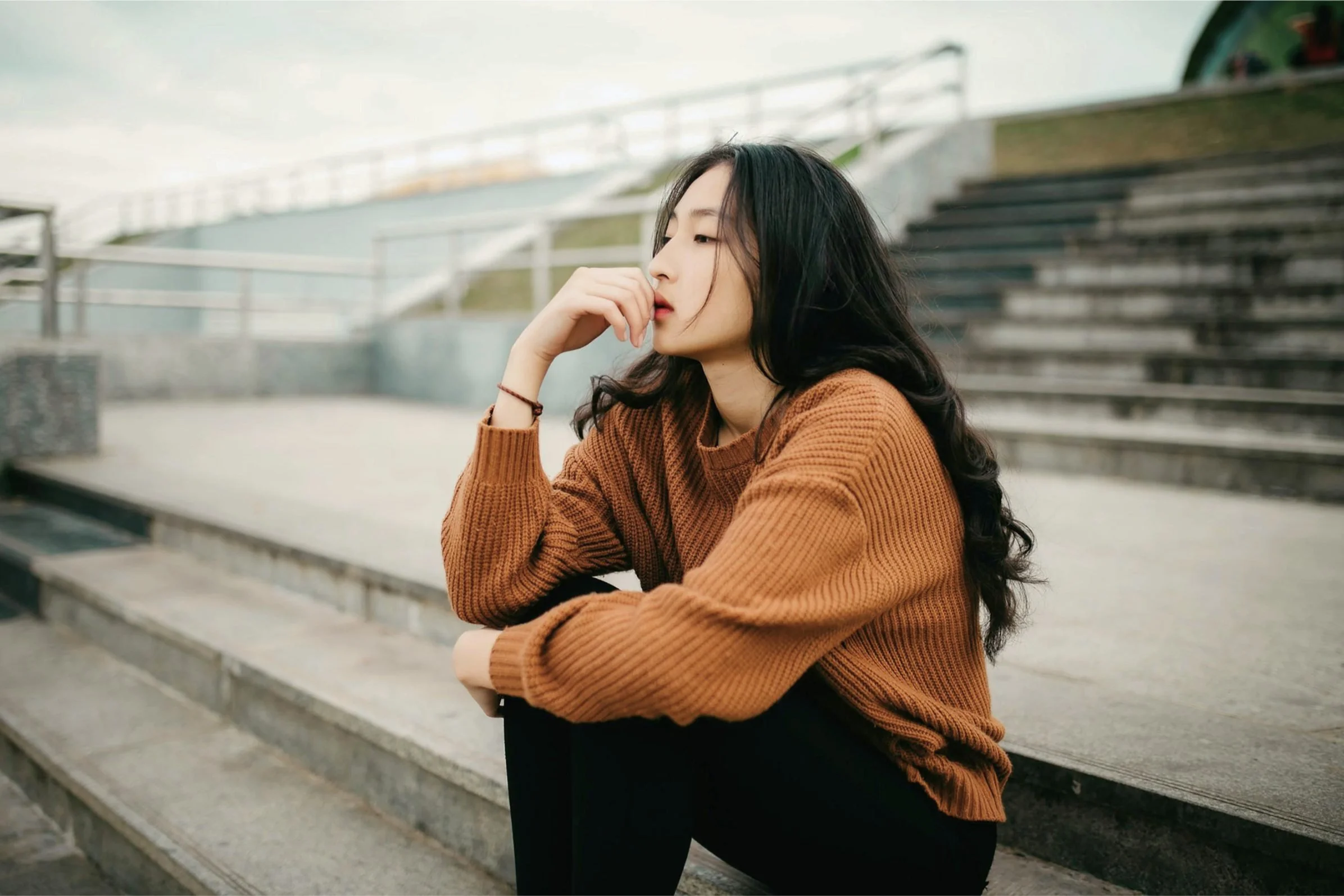 Woman sitting alone on steps, looking thoughtful
