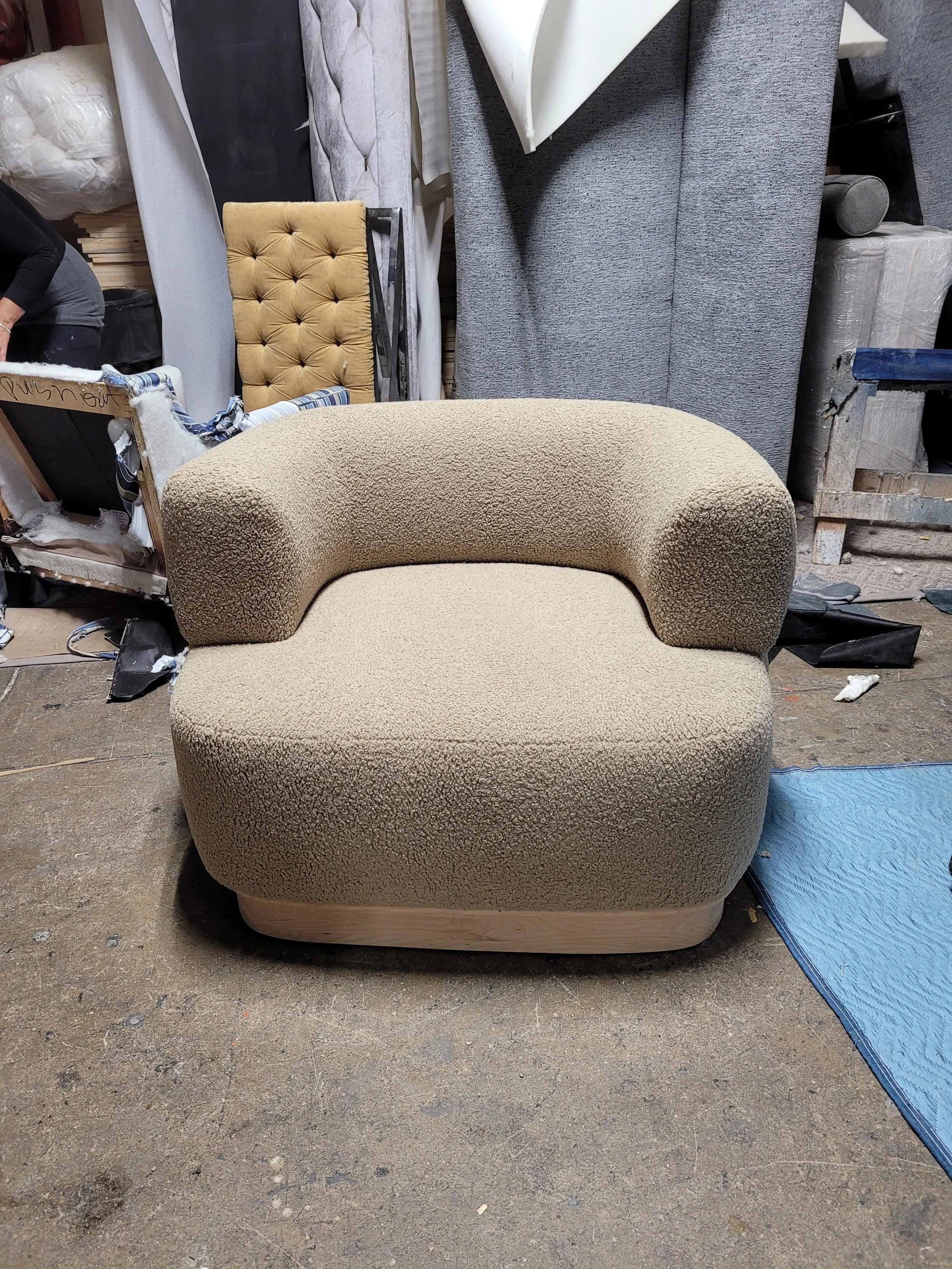 modern rounded beige boucle armchair with a low wooden base.jpg