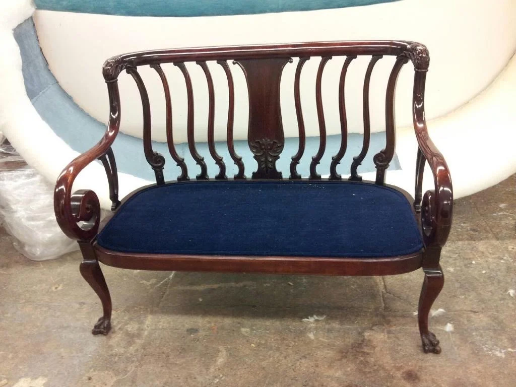 antique-style wooden bench with a blue upholstered seat.jpg
