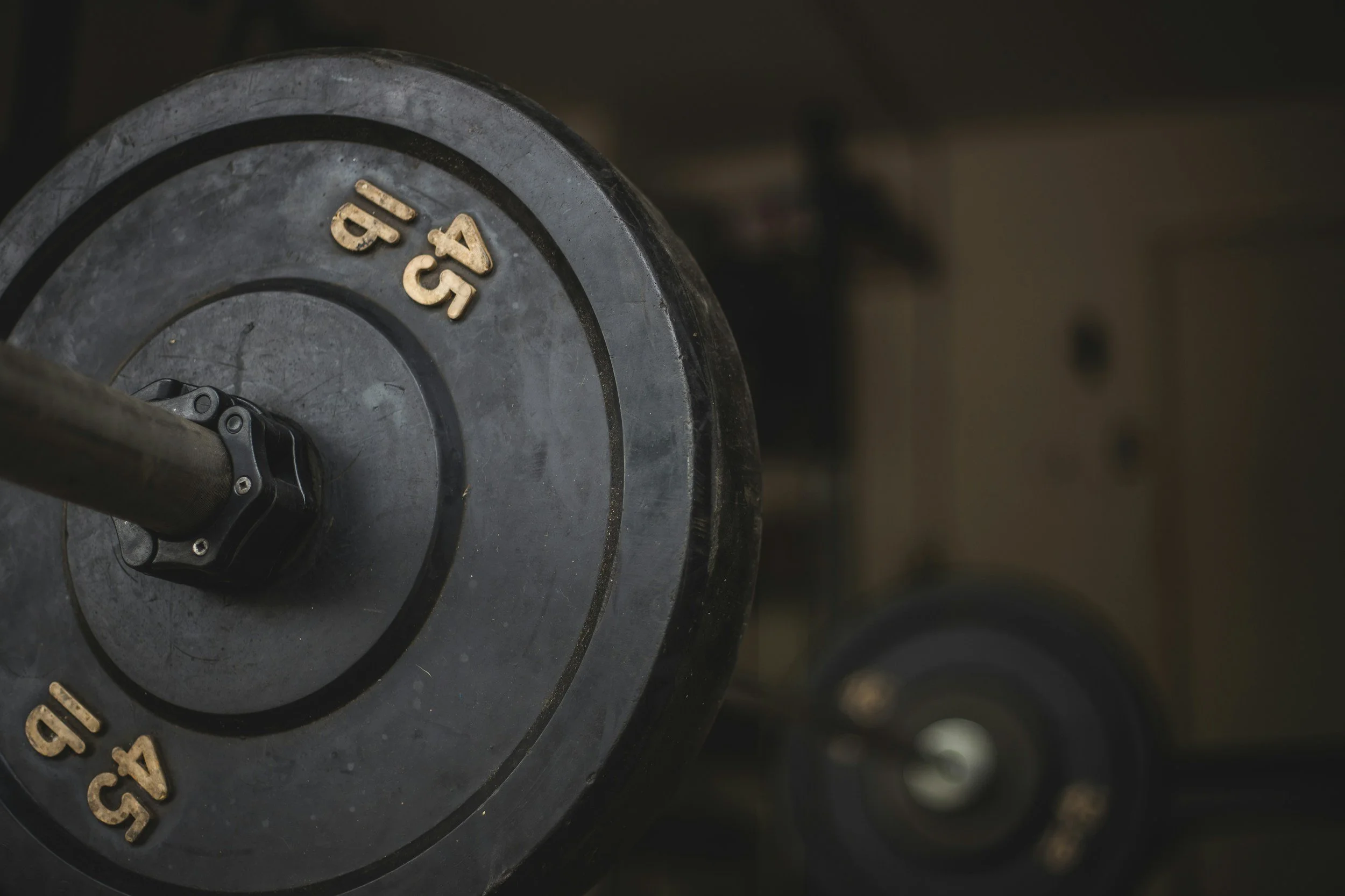 Close-up of a black weight plate labeled '45 lb' on a weightlifting bar.