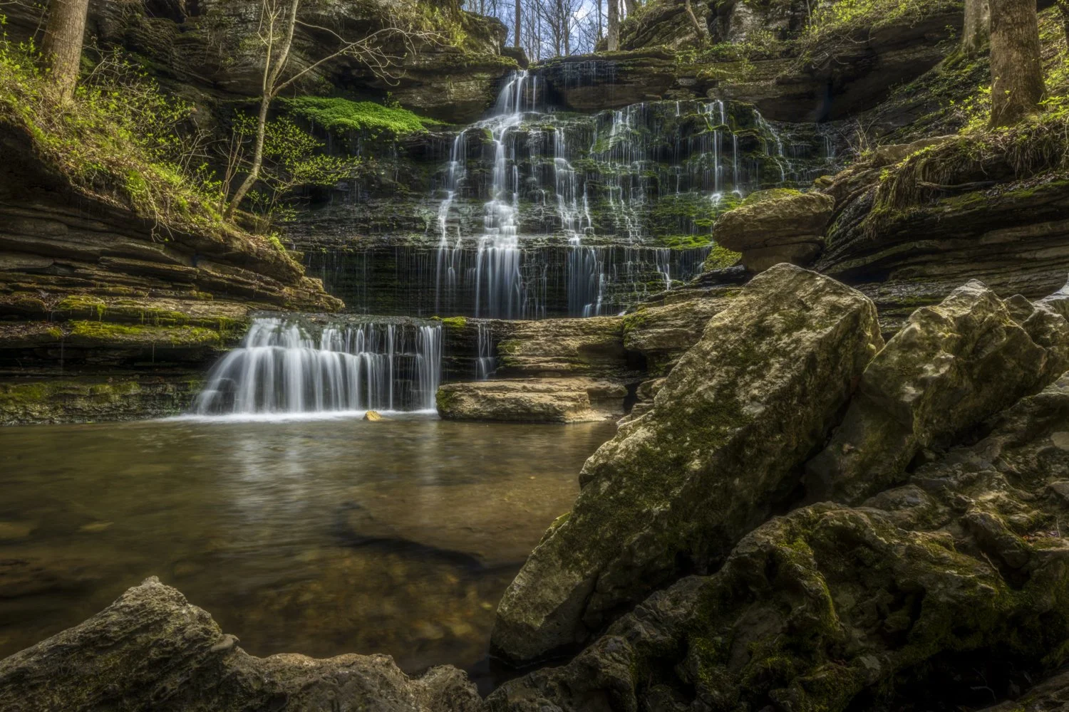 Water flows over moss-covered rocks at Machine Falls into a rocky pool.