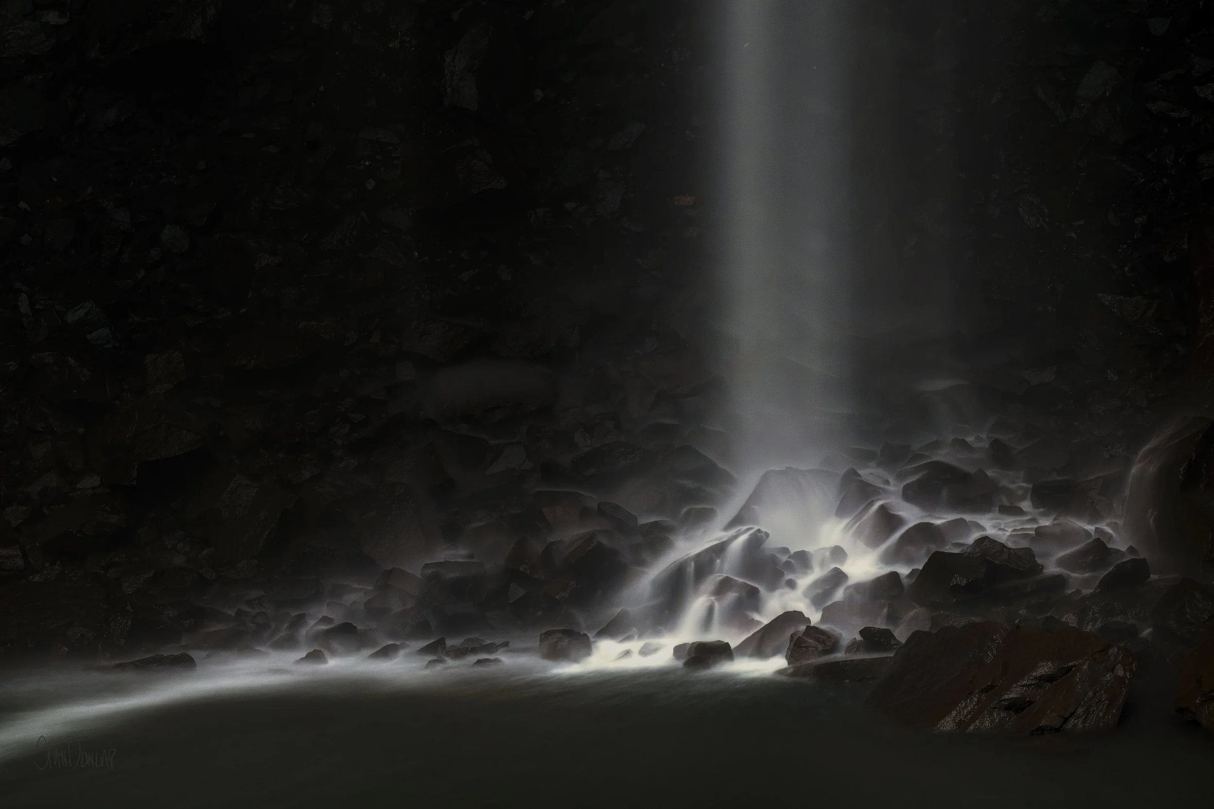 Long exposure photography turns the water of Fall Creek Falls into soft white mist over dark rocks.