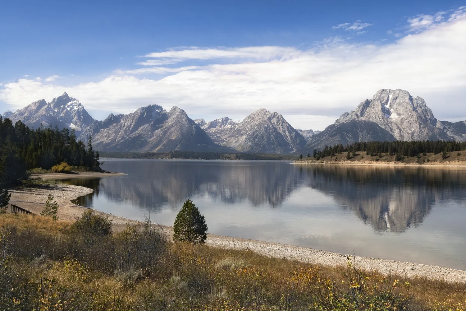 The Teton Range reflected in calm water at Jackson Lake in Grand Teton National Park.