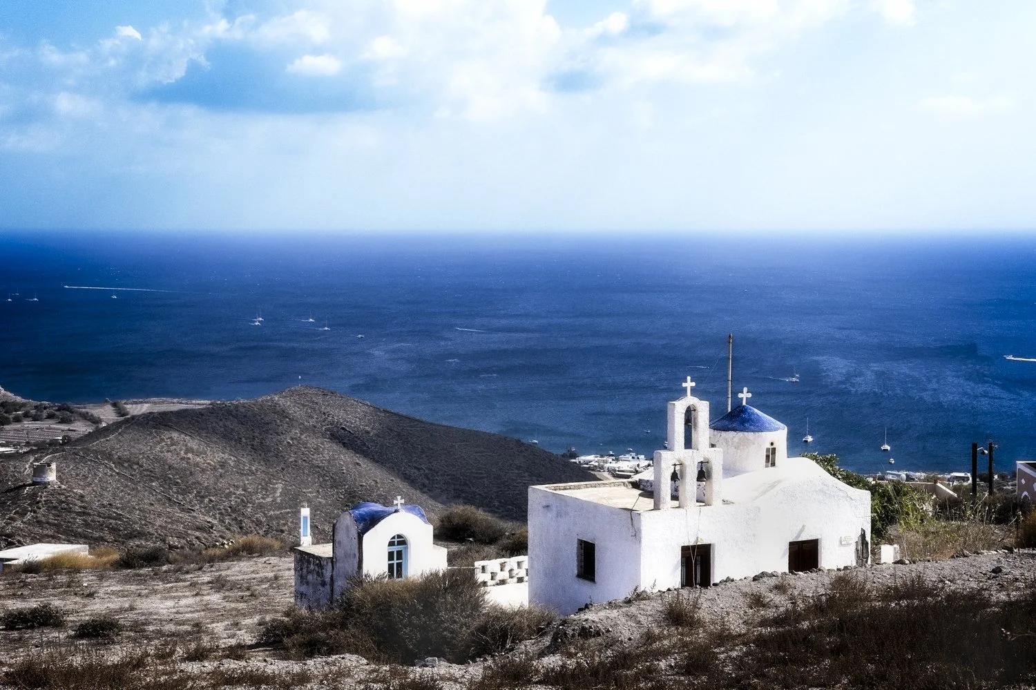 A white church in Santorini overlooking the deep blue Mediterranean Sea.