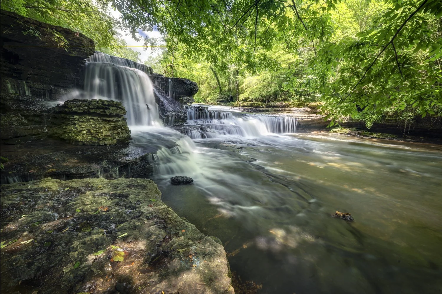 Water cascades over rock ledges in Little Duck River Gorge at Old Stone Fort State Park.