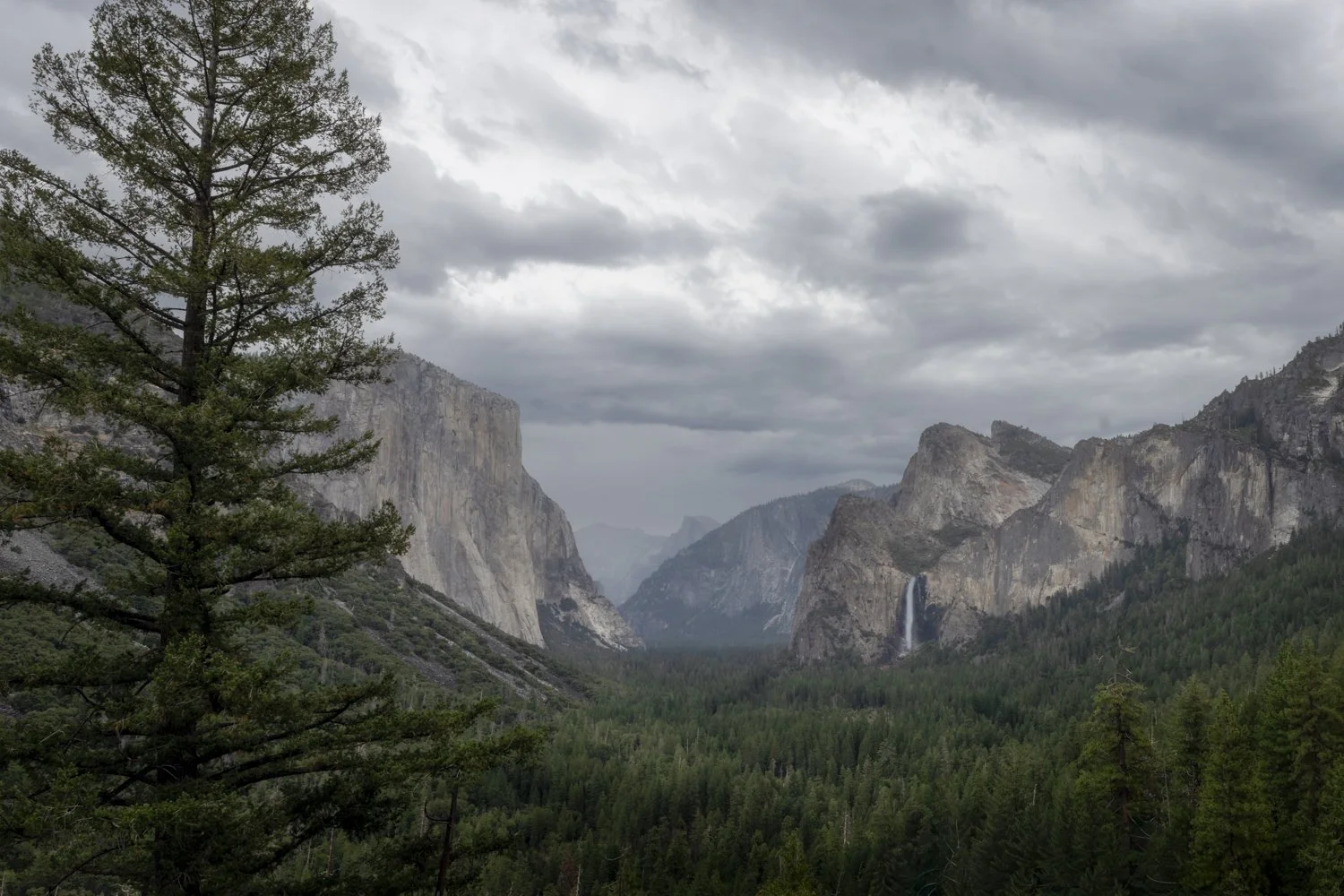 Yosemite Valley and Bridalveil Fall beneath approaching storm clouds at Tunnel View.