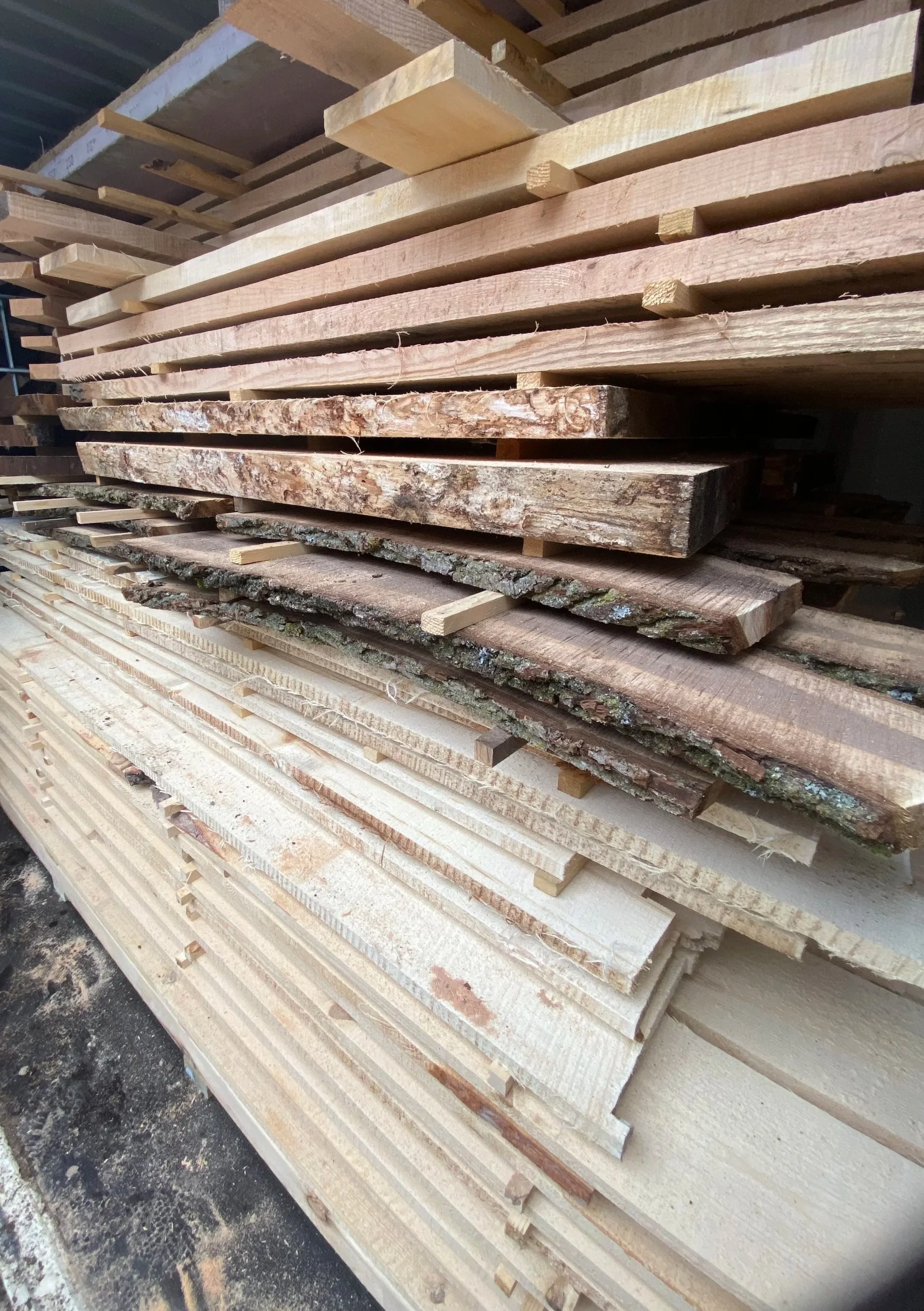 Stacked wood planks and slabs in a warehouse or lumber yard.
