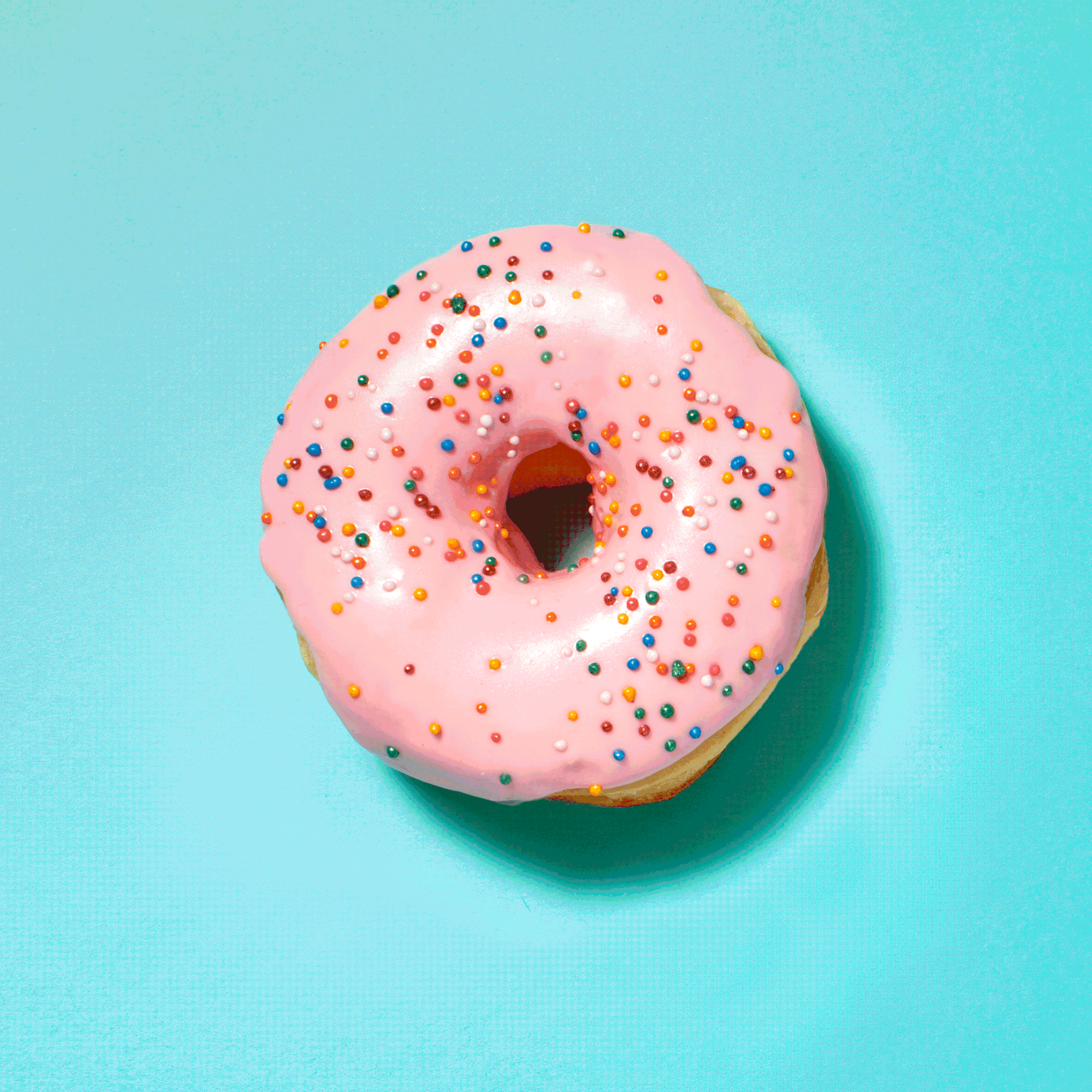 Gif of Pink-frosted donut being eaten, covered in colorful sprinkles on a bright blue background