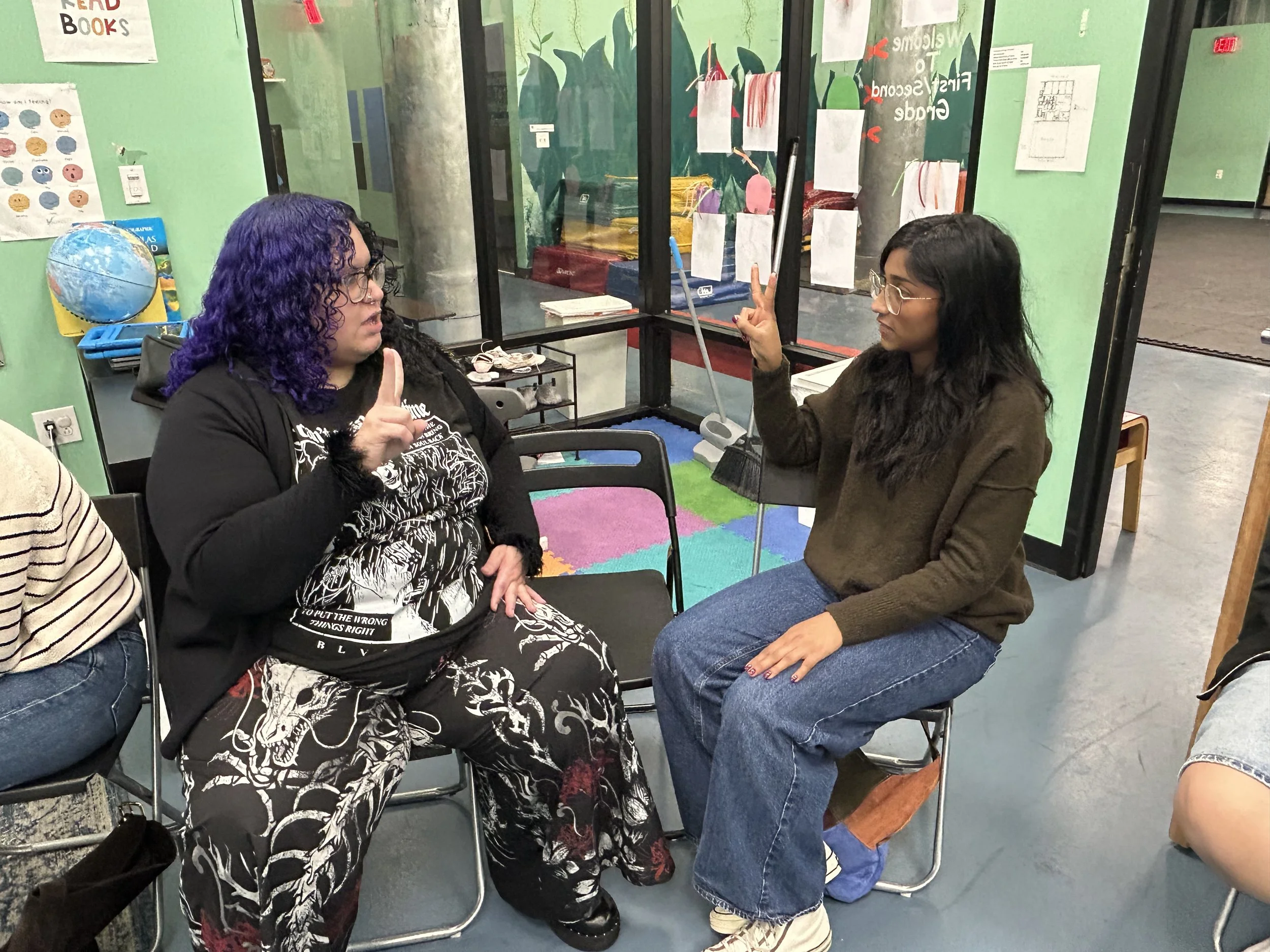 Two students practicing ASL inside a classroom..