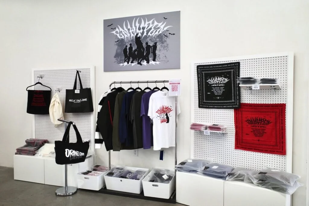 Display of band merchandise including t-shirts, bandanas, and tote bags in a retail store