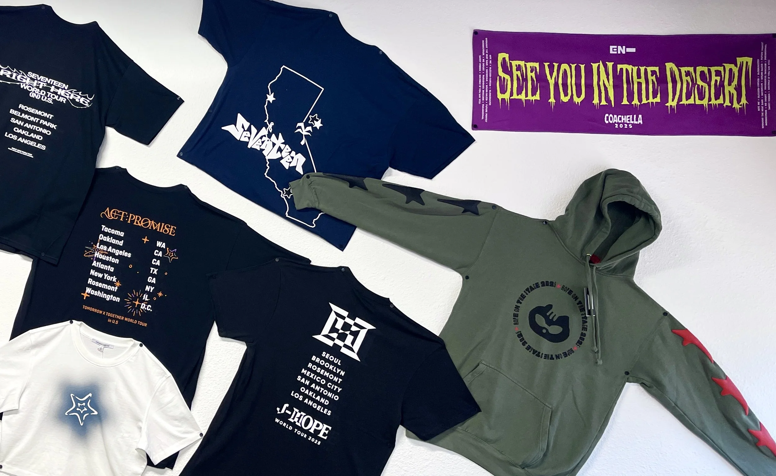Collection of T-shirts, hoodies, and a banner related to the Twenty One Pilots band and their world tour in 2025, displayed on a white wall.