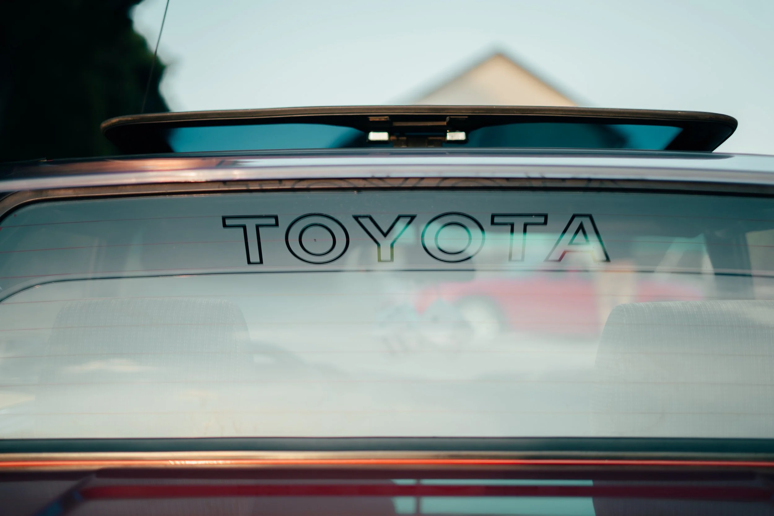 The photo shows the rear view of a car with the Toyota logo on the back window, indicating it is a Toyota vehicle.