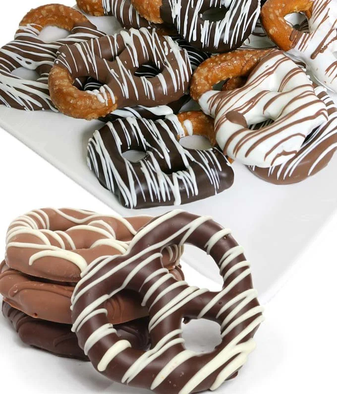 A plate of assorted chocolate and vanilla drizzled pretzels with a stack of chocolate and light-colored glazed pretzels