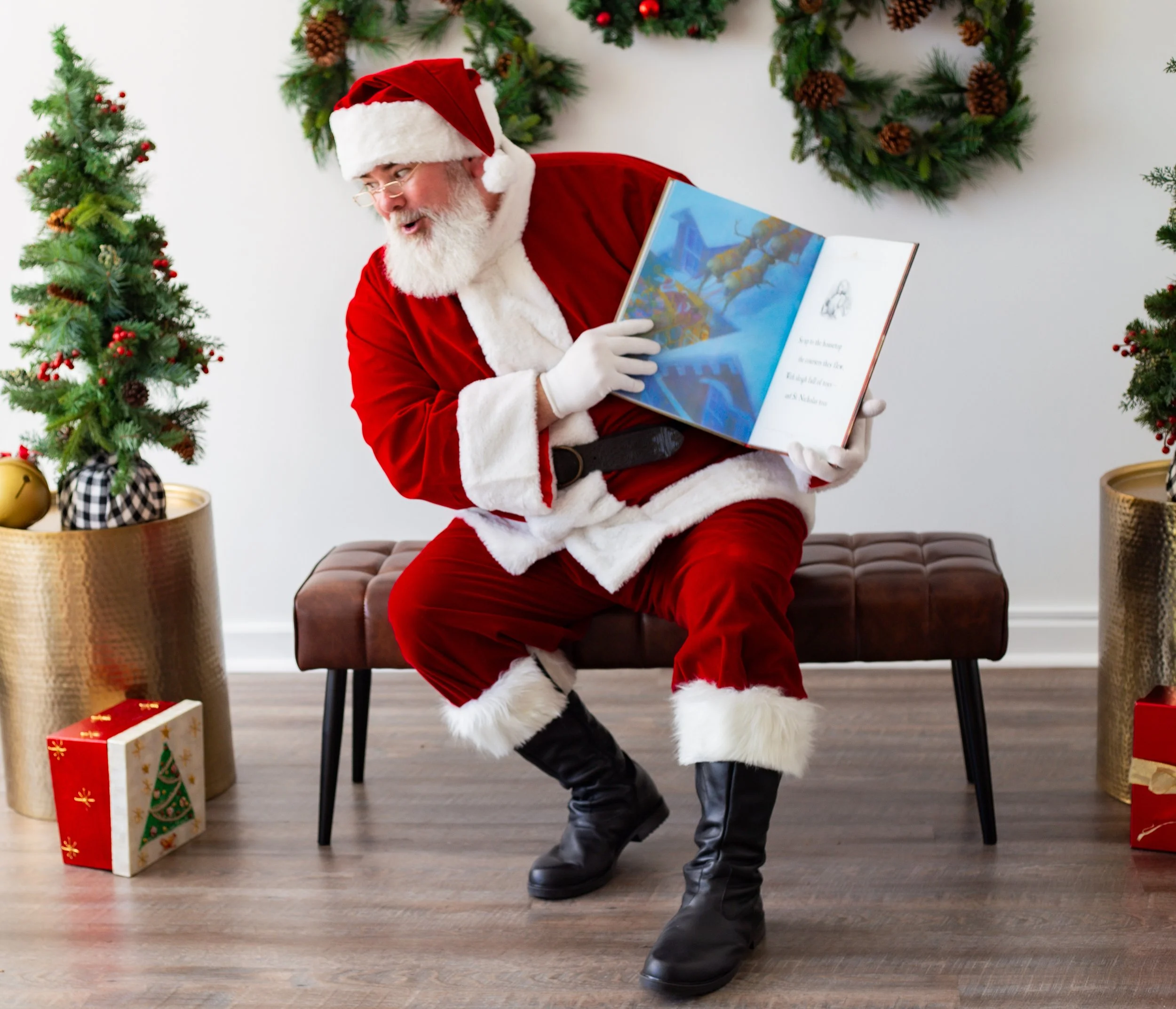 Santa Claus sitting on a bench, looking at a book, with Christmas decorations including garlands and presents around him.