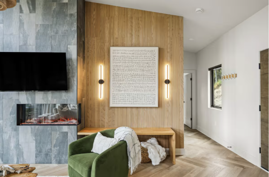 "Modern luxury cabin living room featuring an abstract art accent wall, fireplace, and natural lighting at The Soleil cabin."
