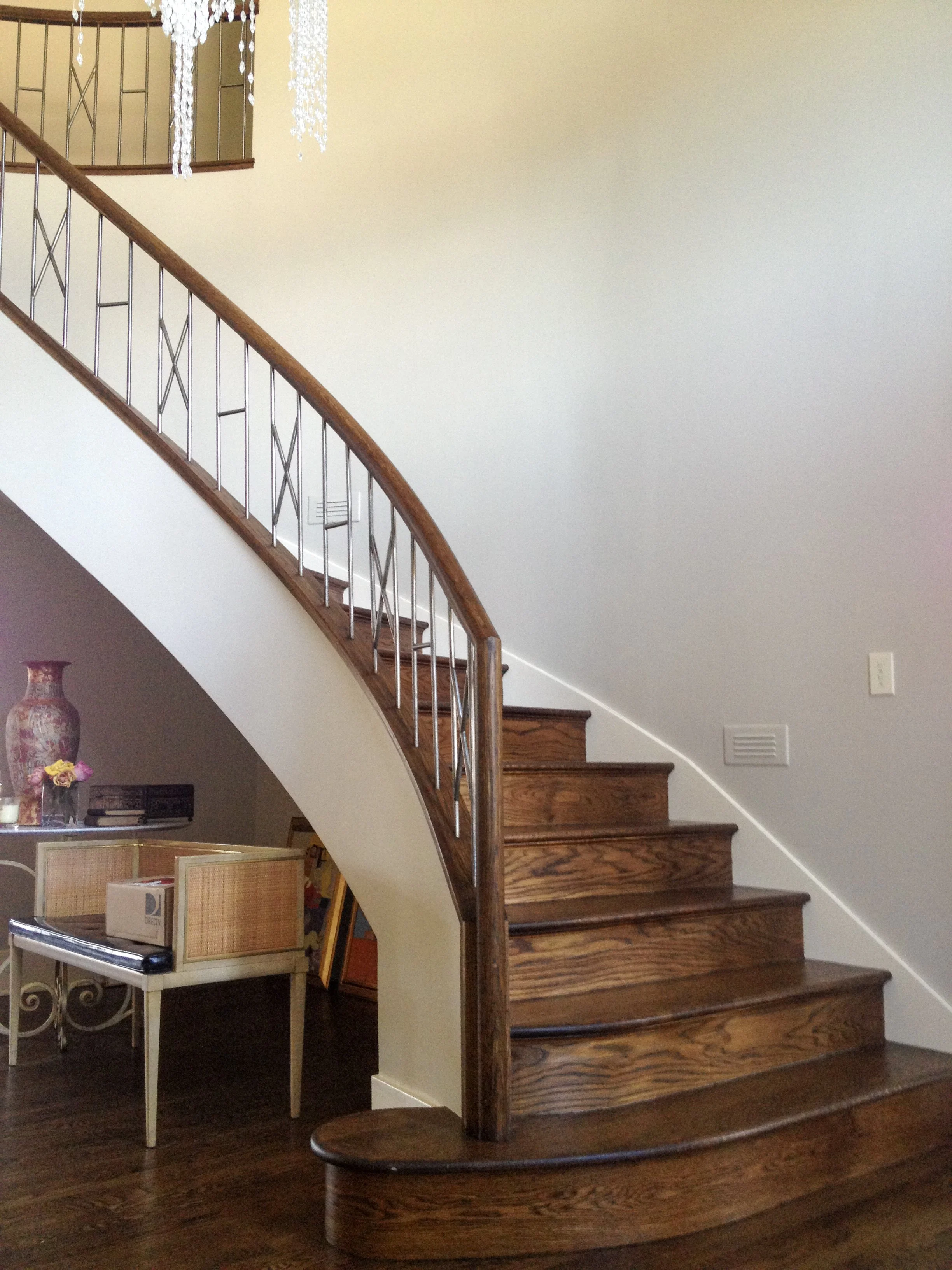 Wooden staircase with metal railings inside a home, part of a living room area with a small table and decorative vases.