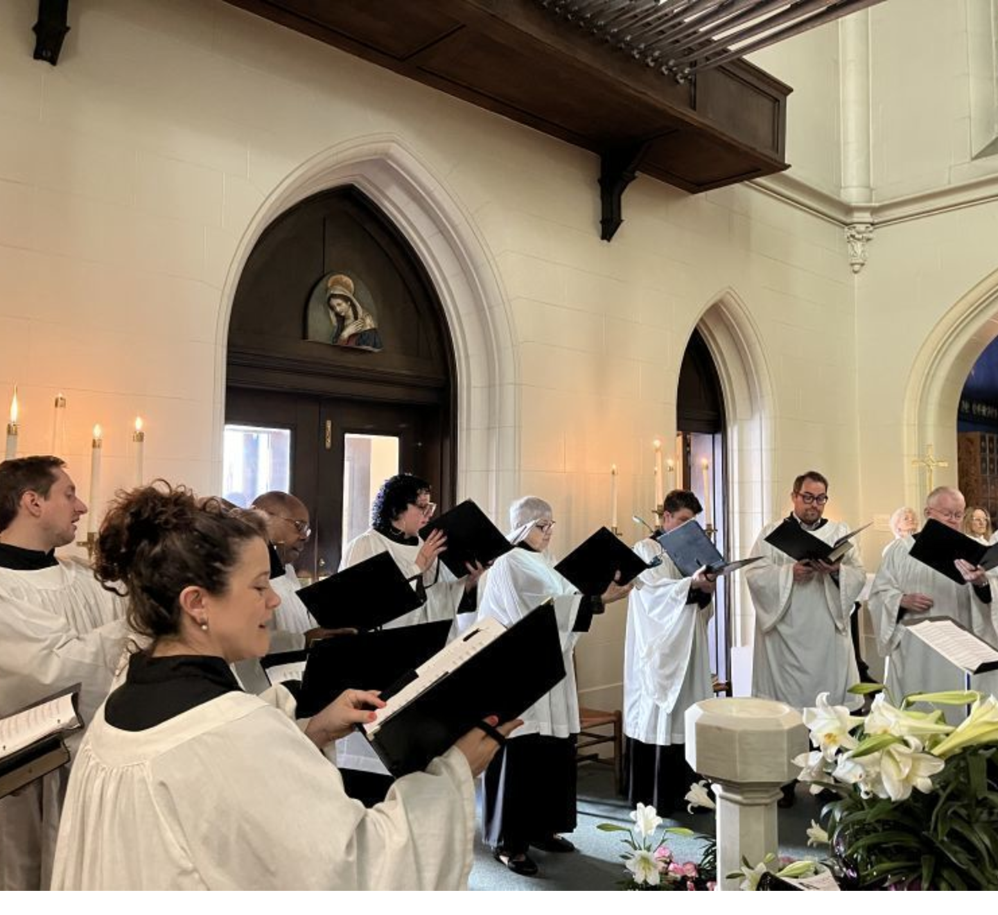 A choir, wearing robes and singing in a church