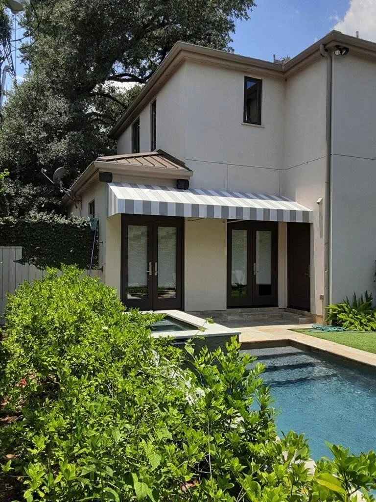 Backside of a modern two-story house with a small pool and green bushes in the backyard.