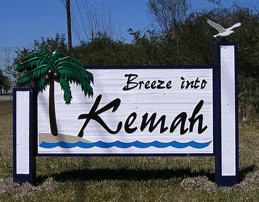 Sign that says "Breeze into Kemah" with a palm tree, waves, and a seagull.