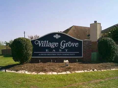 Community entrance sign for Village Grove East with bushes and landscaped area in front.