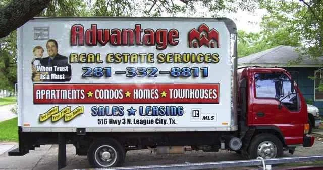 A moving truck with advertising for Advantage Real Estate Services, offering apartments, condos, homes, and townhouses at 516 Hwy 3 N, League City, Texas. The truck displays contact phone number and mentions sales and leasing.