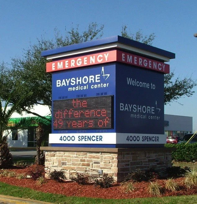 Sign for Bayshore Medical Center emergency entrance at 4000 Spencer, with a digital message board saying 'be prepared for your' and a red cross symbol.