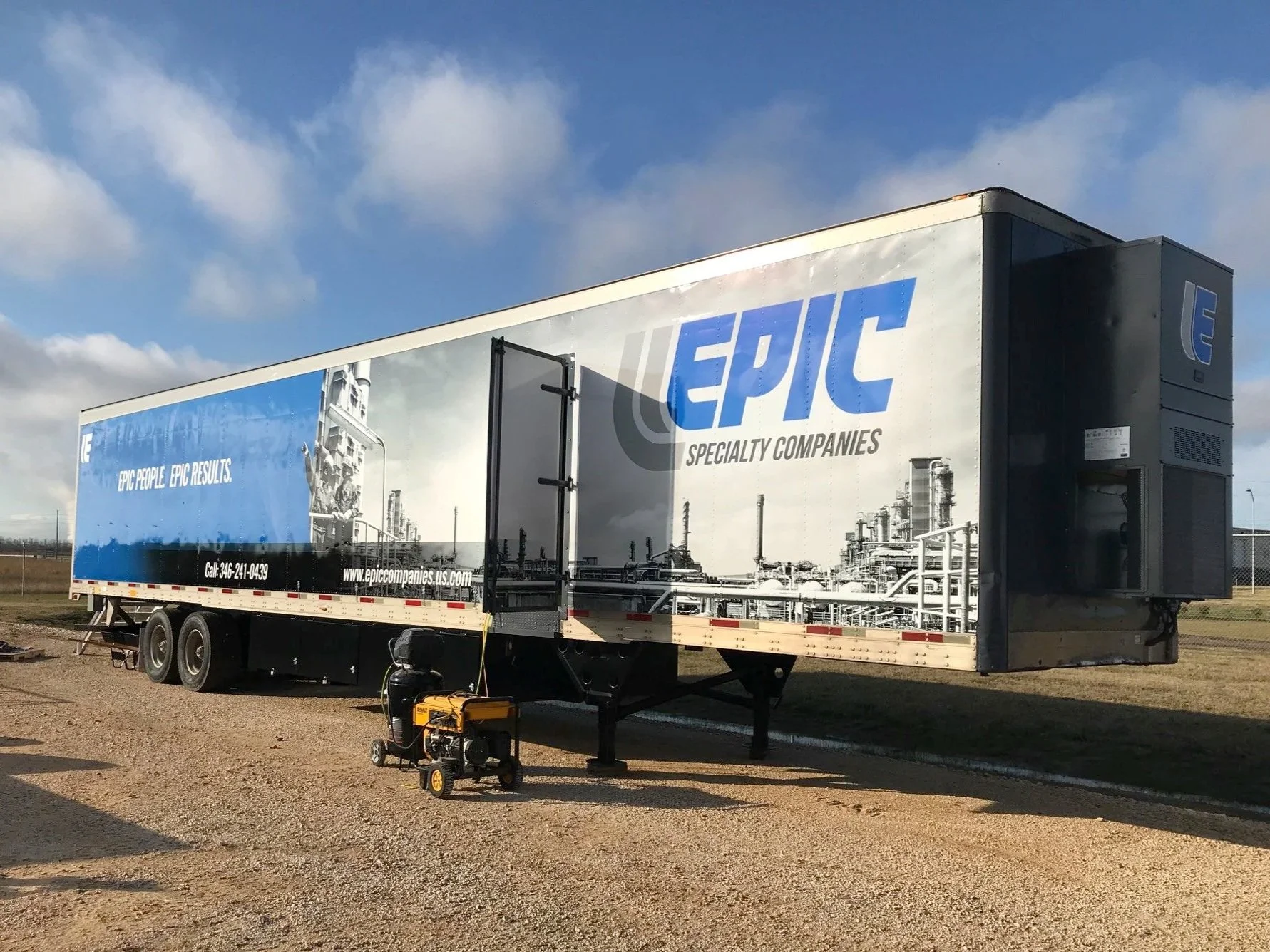 A large trailer with the Epic Specialty Companies logo, featuring a graphic of an industrial plant, is parked on a gravel lot under a partly cloudy sky. Equipment and a generator are positioned nearby.
