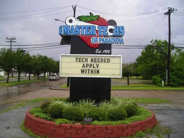 Sign for Master Techs of Pasadena with a strawberries and blackberries graphic, and a message board reading 'Tech needed apply within'.