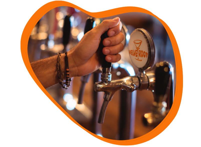 A person's hand pulling a tap handle on a beer tap at a bar, with the Velvet Root logo visible on the tap