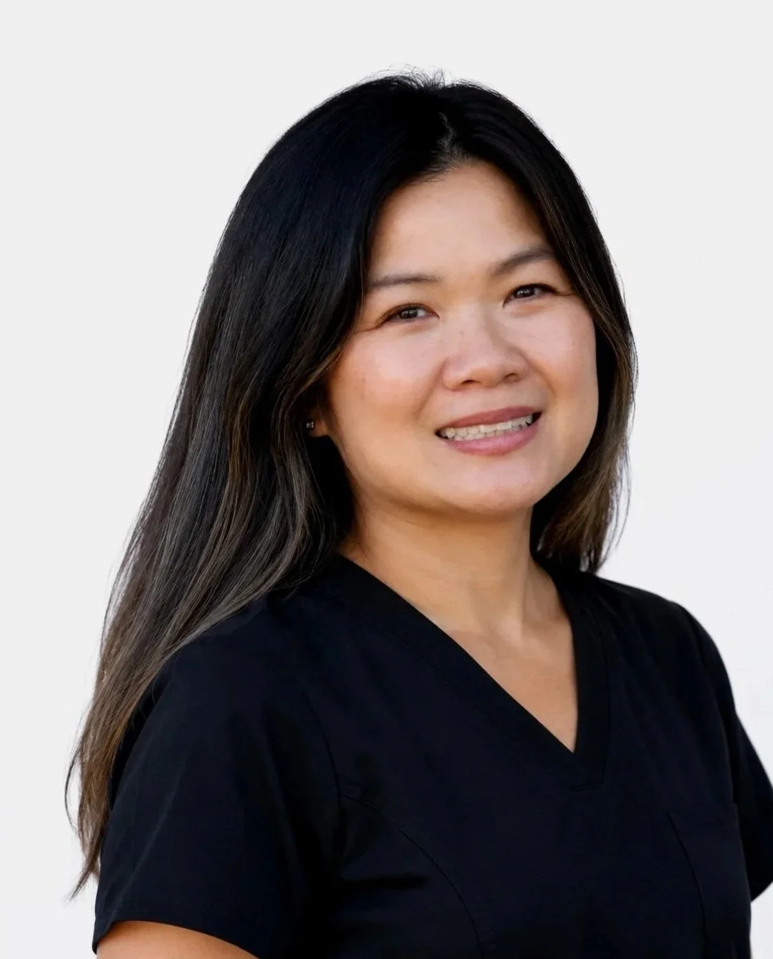 Portrait of a woman with long dark hair wearing a black top, smiling against a plain white background.