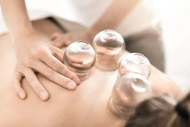 Person receiving cupping therapy with glass cups on their back during a massage session.