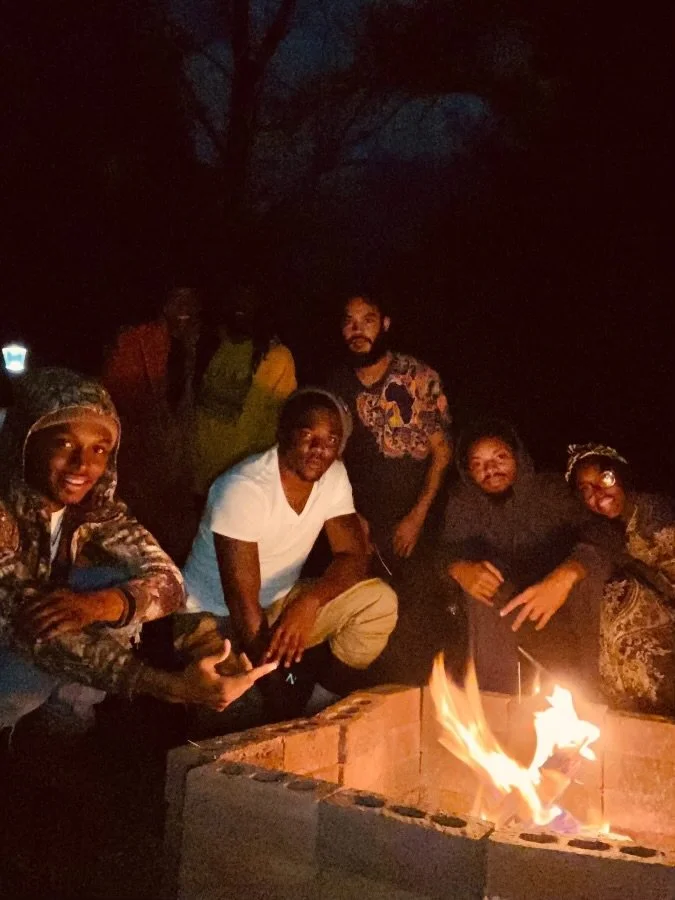 Israelites gathered around a campfire outdoors at night, smiling and enjoying each other's company. New Legacy Initiative. New Legacy, Inc.