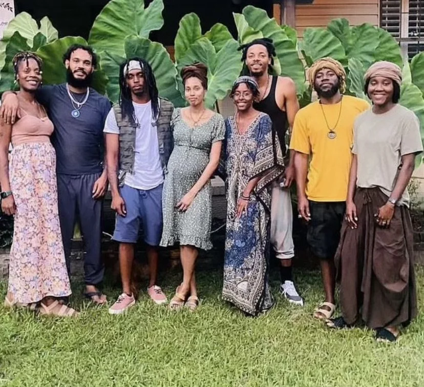 Group of eight people (Israelites) standing outdoors in front of large green leaves, smiling for the photo. New Legacy Initiative. New Legacy, Inc.