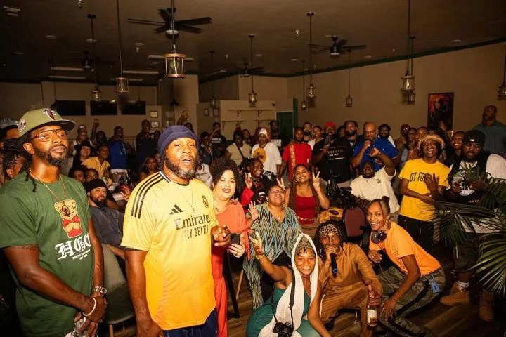 Group of people (Israelites) gathered in an indoor venue, some standing, some seated, smiling and enjoying an event or gathering. New Legacy Initiative. New Legacy, Inc.