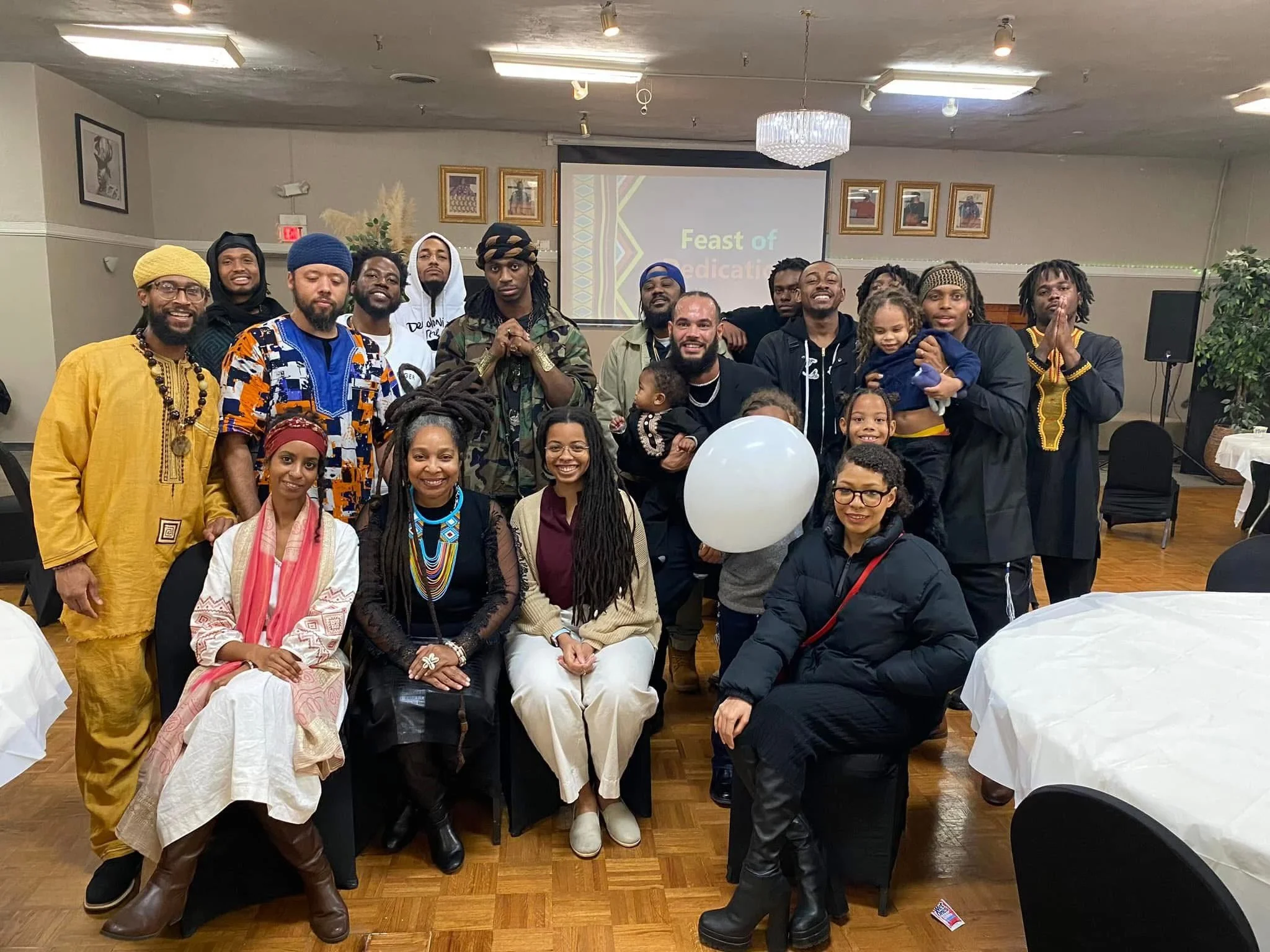 Group of people (Israelites) gathered in a celebration, with a presentation slide in the background reading 'Feast of'. New Legacy Initiative. New Legacy, Inc.