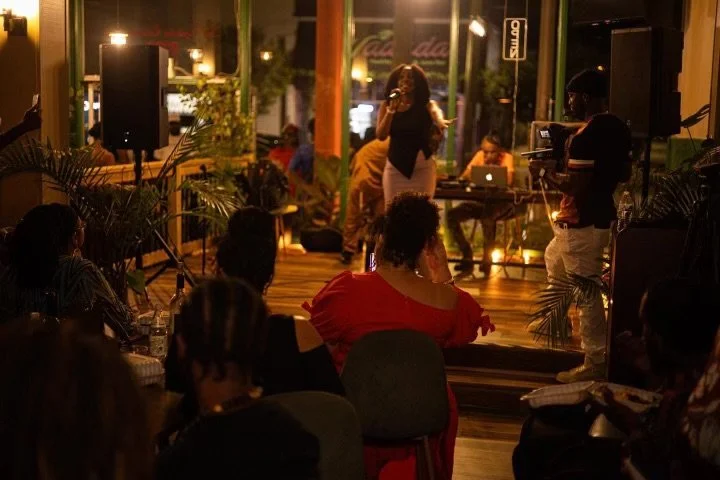 An Israelite woman singing on stage with a microphone in hand at an indoor event. New Legacy Initiative. New Legacy, Inc.
