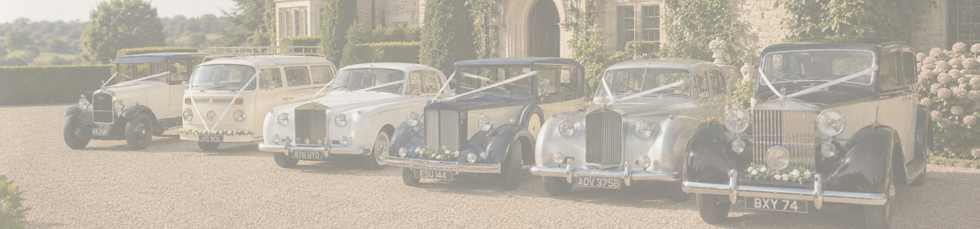Six vintage wedding cars parked in a line in front of a grand building with landscaping, blooming flowers, and greenery in west sussex