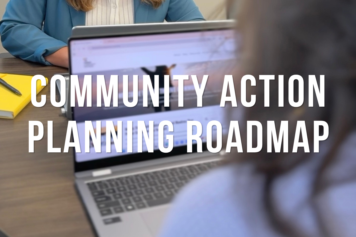 People working together at a table with documents, notebooks, and a smartphone, planning and organizing a community action project.
