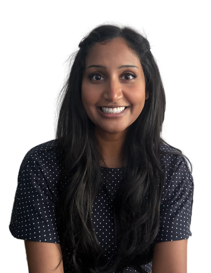 A woman with long dark hair and a bright smile, wearing a dark polka dot shirt.